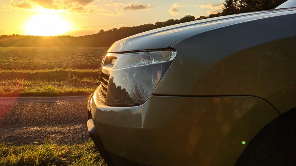 alt=“Dacia Duster steht im Sonnenuntergang vor einem Feld″
