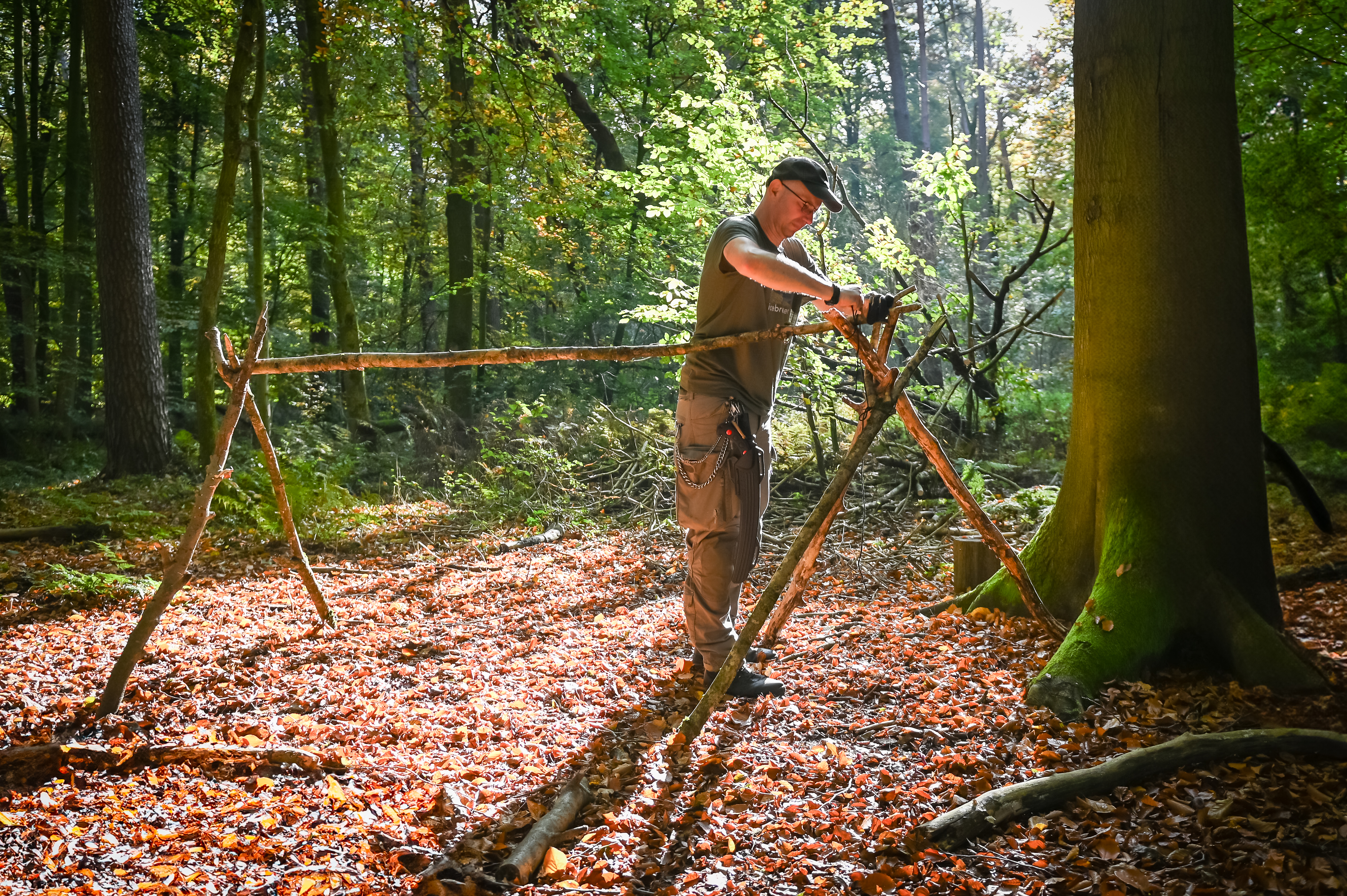 alt="Bushcraft-Tisch aus einer Baumscheibe und drei Stöcken auf Waldboden"