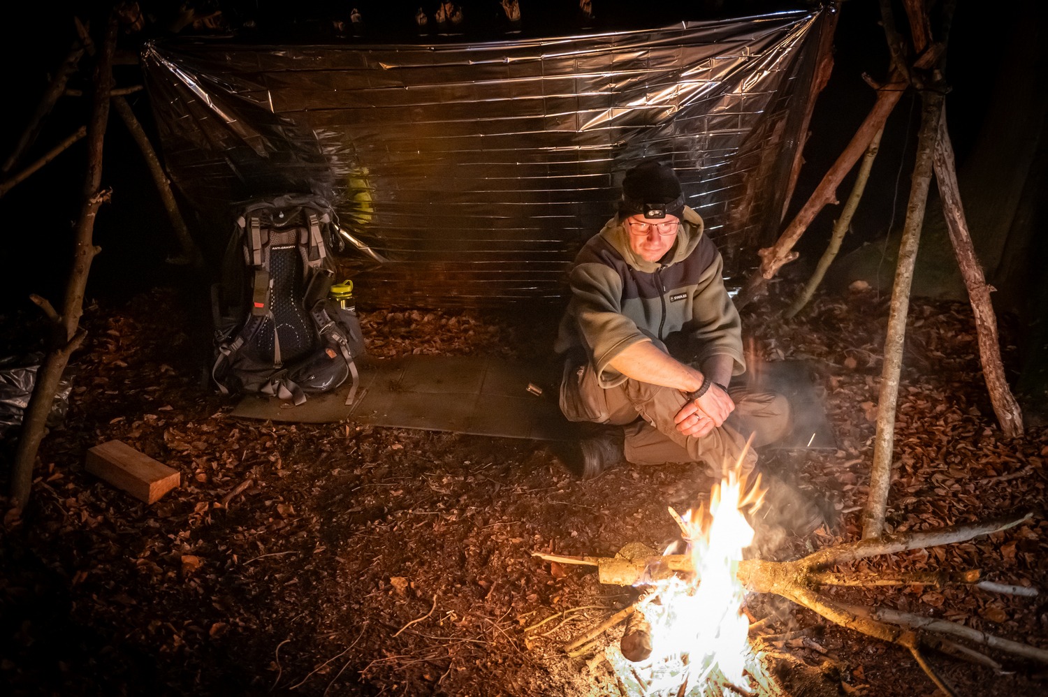 alt=“Tarp mit Schaffell und Schlafsack auf dem Waldboden″