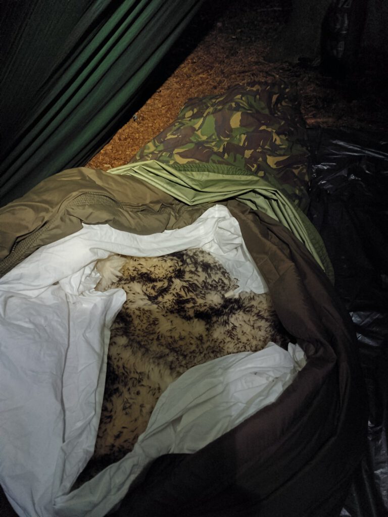 Schaffell als natürliche Bodenisolierung im Schlafsack bei Waldübernachtung