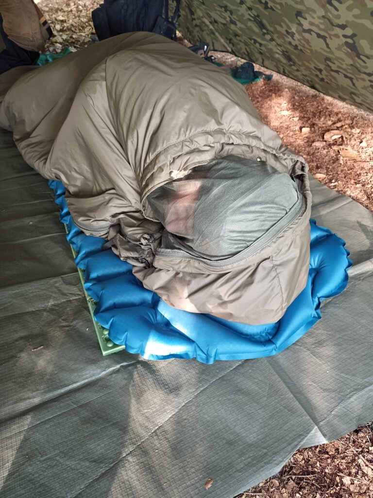 Kunstfaserschlafsack mit Insektennetz unter Tarp im Wald