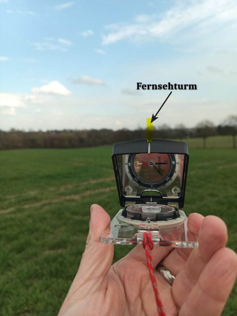 Peilung mit Spiegelkompass auf markantes Objekt in der Landschaft